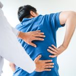 doctor looking at lower back on man