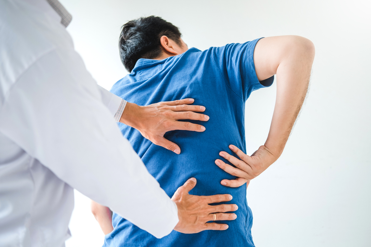 doctor looking at lower back on man